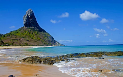 Fernando de Noronha coastline with Morro do Pico, clear waters, and sandy beach.