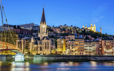 Lyon cityscape with Saint George's Church and Basilica of Notre-Dame de Fourvière at dusk.