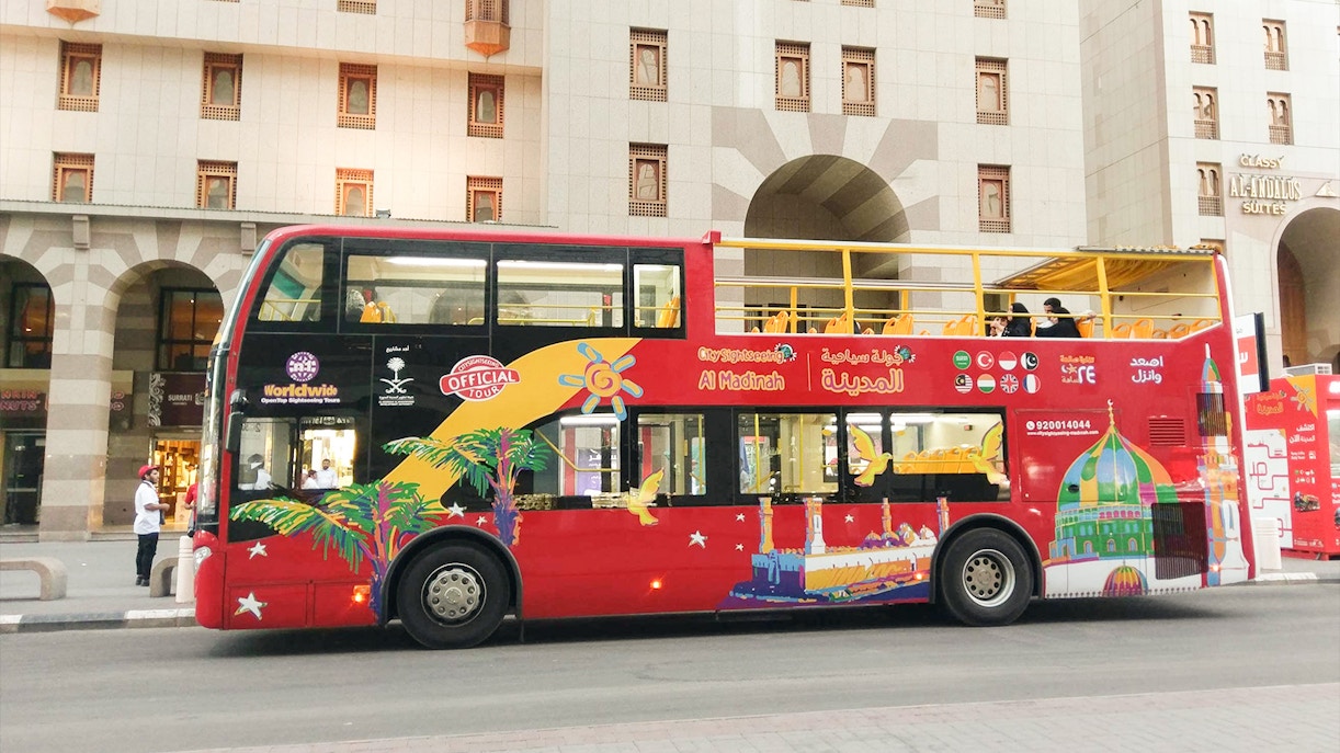 Tourists enjoying the Al Madinah Hop-On-Hop-Off Bus Tour with a view of the city's landmarks in Riyadh, Saudi Arabia