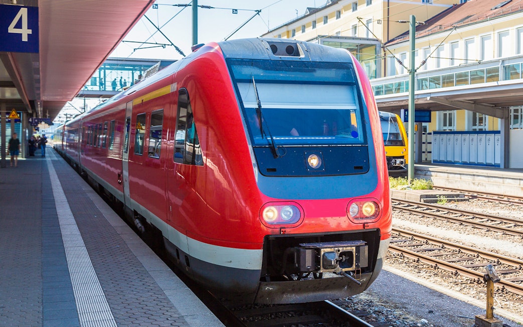 Red train at Munich station for Neuschwanstein Castle tour transfer.