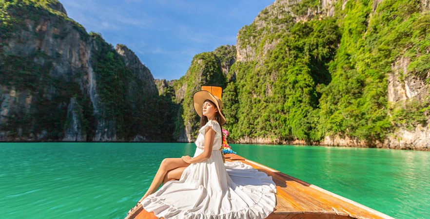 Woman in white dress on longtail boat, Maya Bay, Phi Phi Islands tour.