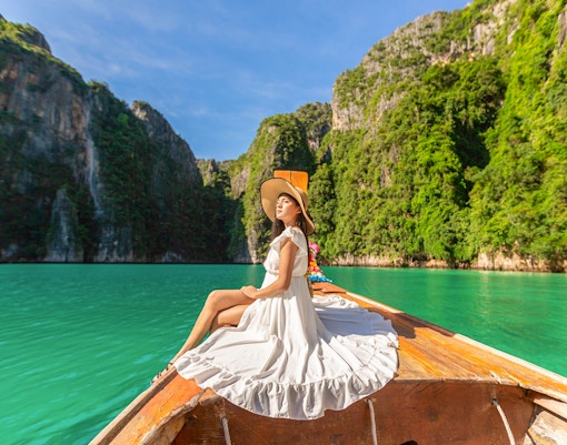 Woman in white dress on longtail boat, Maya Bay, Phi Phi Islands tour.