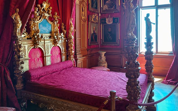Miramare Castle bedroom with ornate bed and historical furnishings in Trieste, Italy.