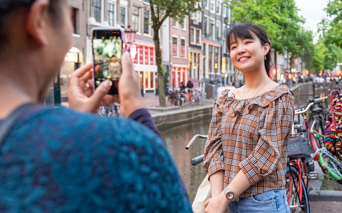 Tourists photographing in Amsterdam's red light district by a canal.