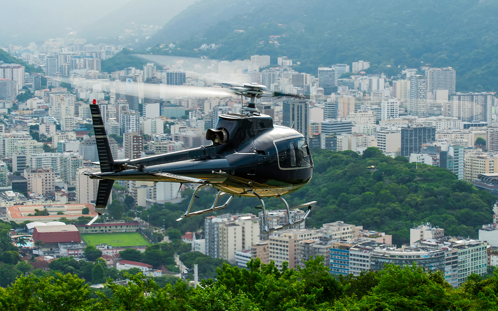 Helicopter taking off over Rio de Janeiro cityscape.