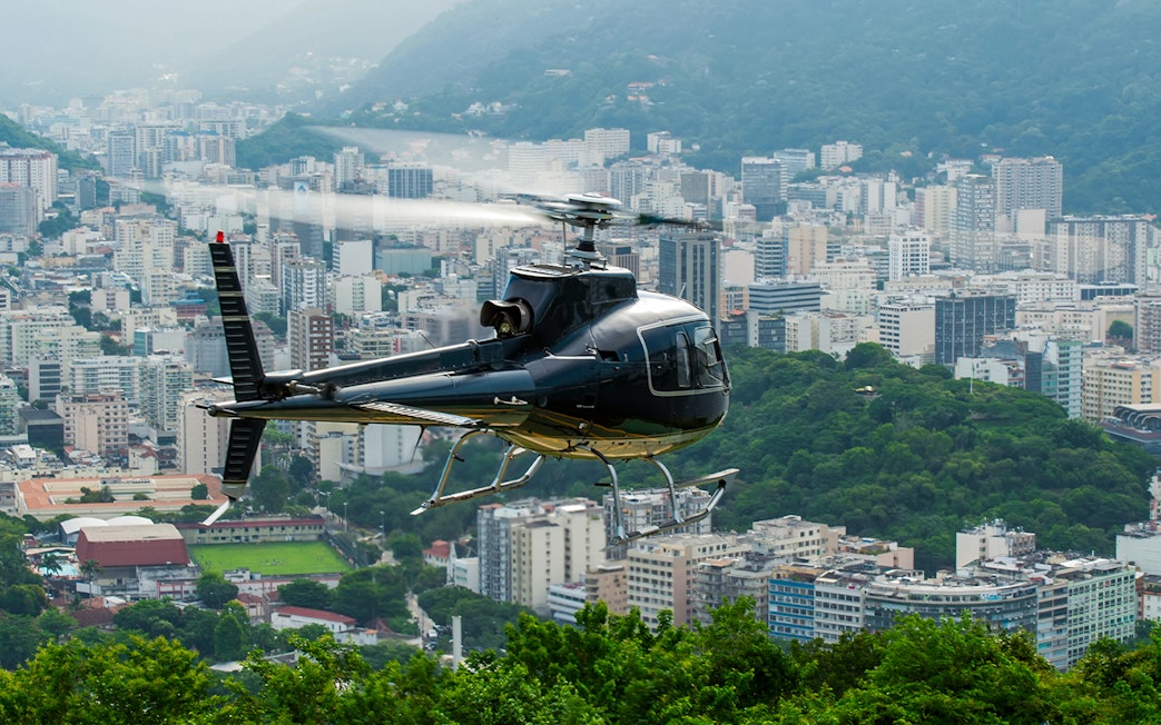 Helicopter taking off over Rio de Janeiro cityscape.