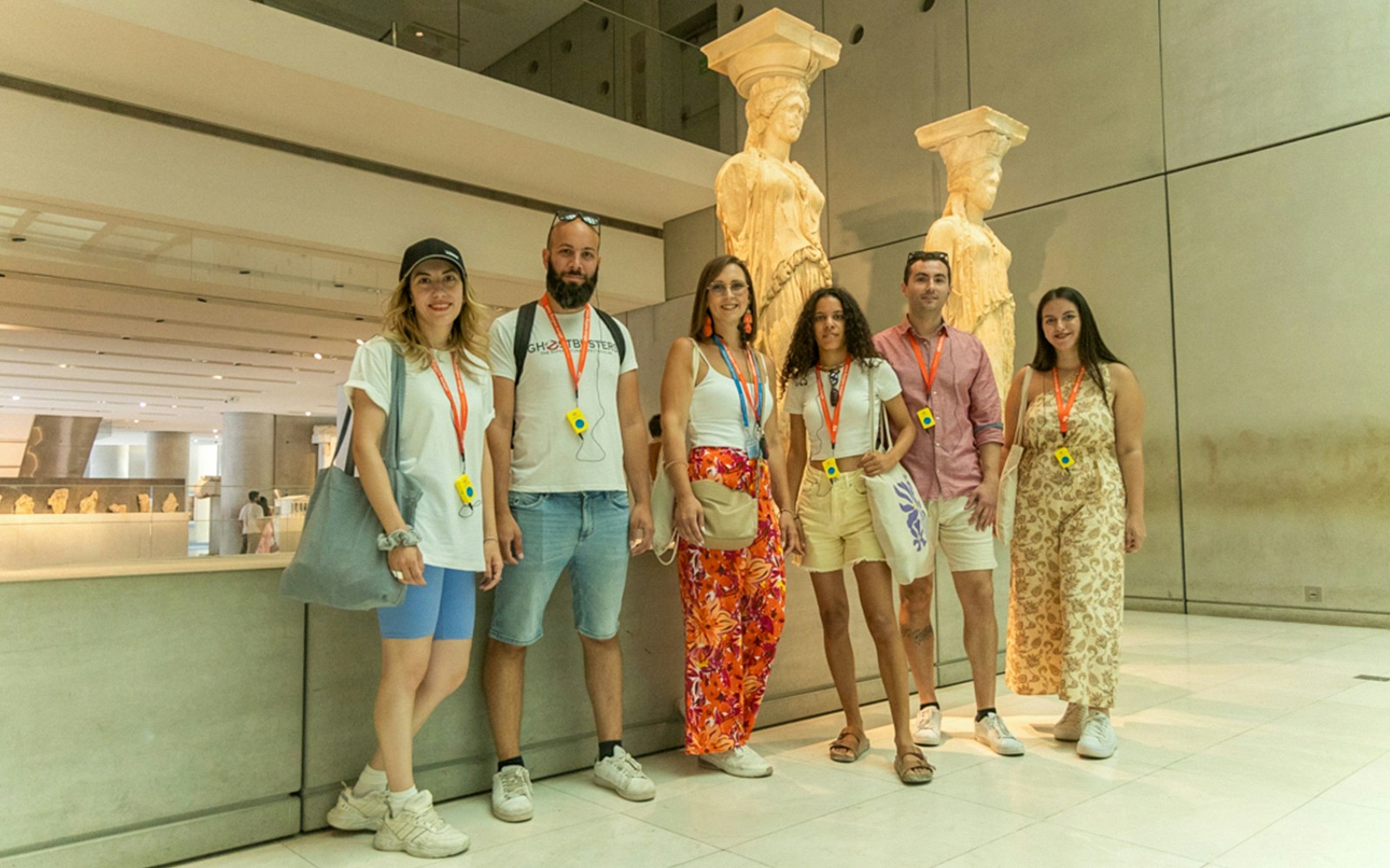 Visitors on a guided tour at the Acropolis Museum, standing by Caryatid statues.