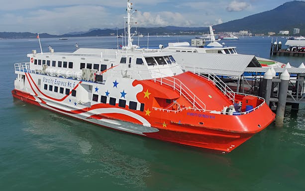 Langkawi ferry docked at the pier with scenic mountain backdrop.
