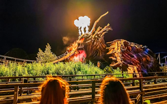 Roller coaster with dragon sculpture and fire effects at Heide Park Halloween event.