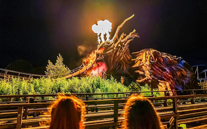 Roller coaster with dragon sculpture and fire effects at Heide Park Halloween event.