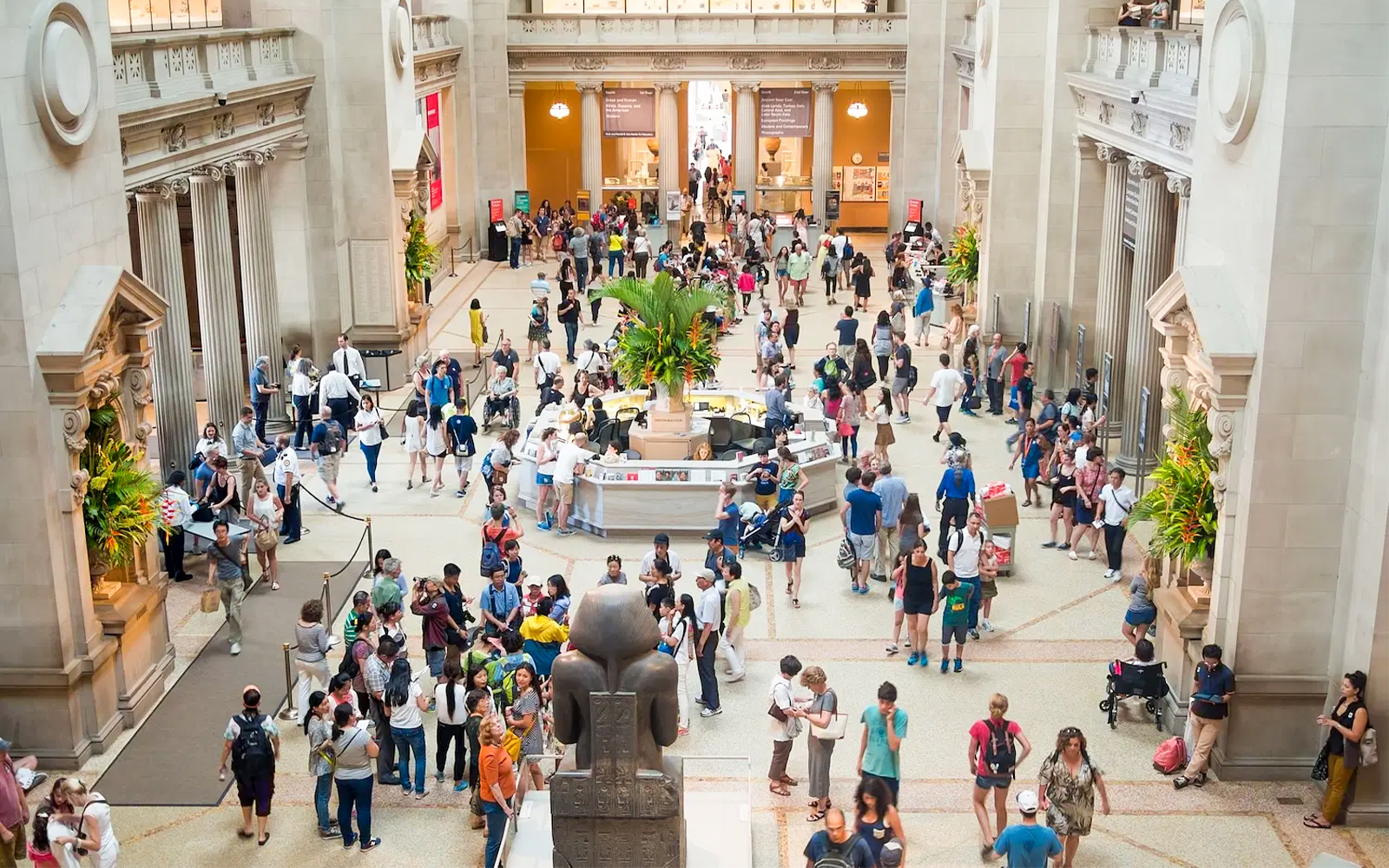 Crowded entrance hall of The Met Museum with visitors exploring exhibits.