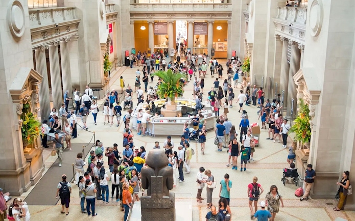 Crowded entrance hall of The Met Museum with visitors exploring exhibits.