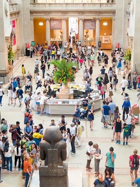 Crowded entrance hall of The Met Museum with visitors exploring exhibits.