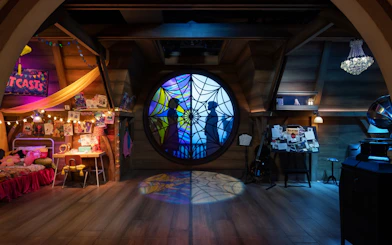 Stained glass window with silhouettes on the Wednesday play set, Netflix House, Philadelphia.