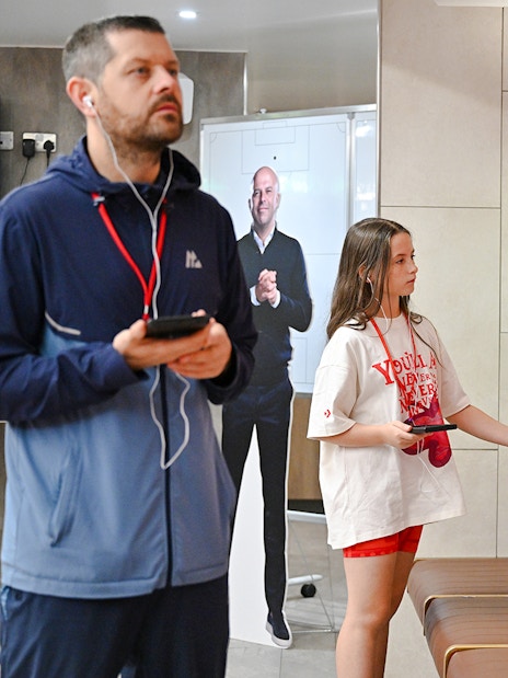Visitors exploring the players' dressing room at Anfield Arena with team jerseys displayed.