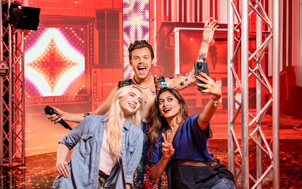 Two women taking a selfie with Harry Styles's wax figure at Madame Tussauds, New York.