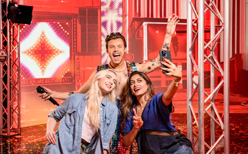 Two women taking a selfie with Harry Styles's wax figure at Madame Tussauds, New York.