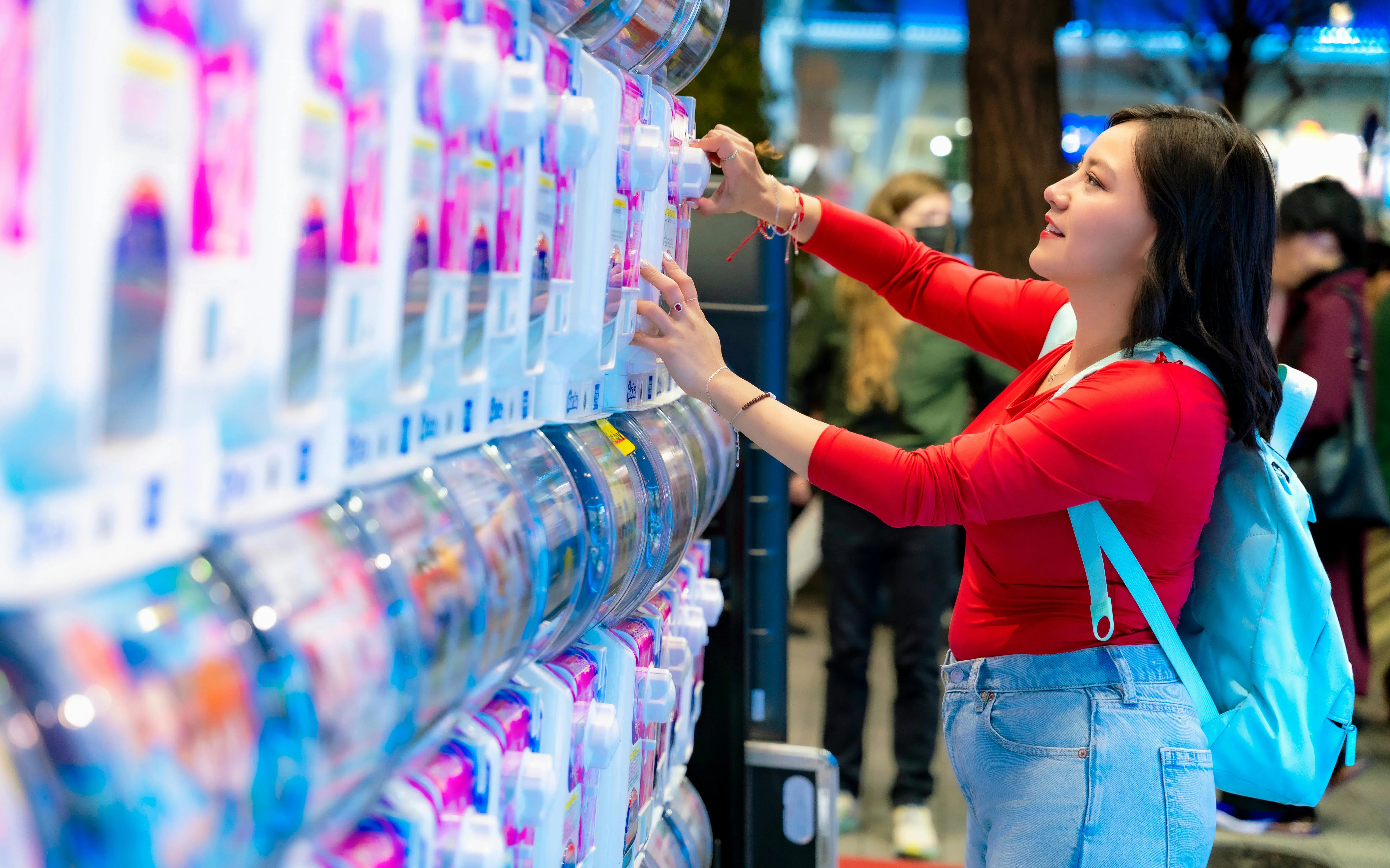 Young woman playing arcade games in Akihabara, Tokyo, Japan, with glowing screens.