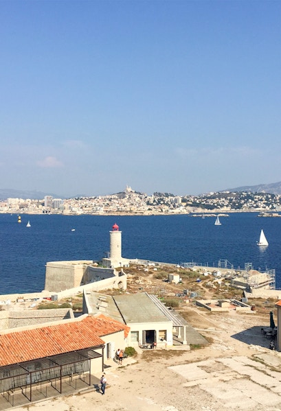 Château d’If with lighthouse and Marseille skyline in the background, France.