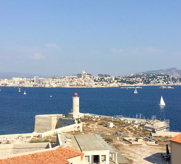Château d’If with lighthouse and Marseille skyline in the background, France.