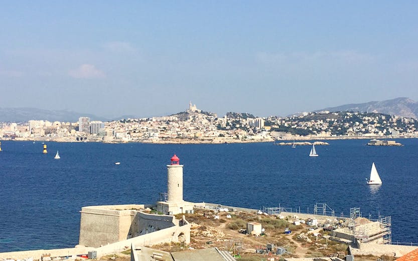 Château d’If with lighthouse and Marseille skyline in the background, France.