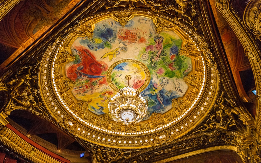 Ceiling of Opera Garnier in Paris with colorful fresco and ornate chandelier.