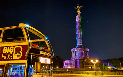 Open-top bus near Berlin's Victory Column illuminated during the Berlin Lights Festival.