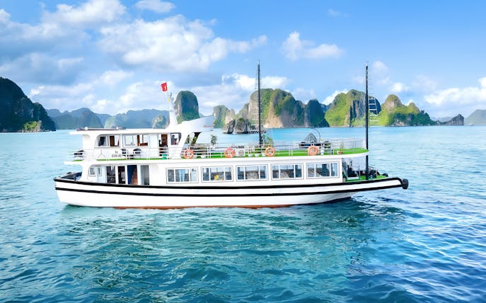 Ha Long Bay cruise ship passing limestone karsts, Vietnam.