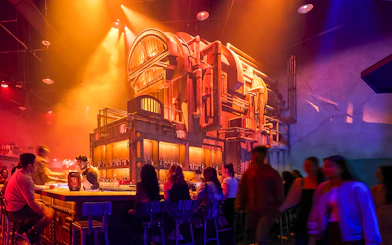 Bar scene at Universal Horror Unleashed, Las Vegas, with patrons enjoying drinks under dramatic lighting.