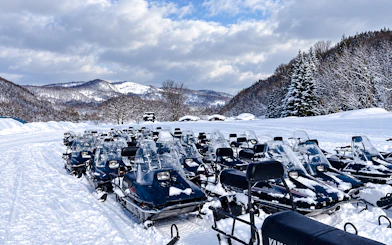 Snowmobiles lined up in snowy landscape, Sapporo tour, Hokkaido.