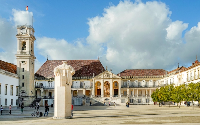 University of Coimbra courtyard with clock tower and statue, part of Fátima & Coimbra tour from Porto.