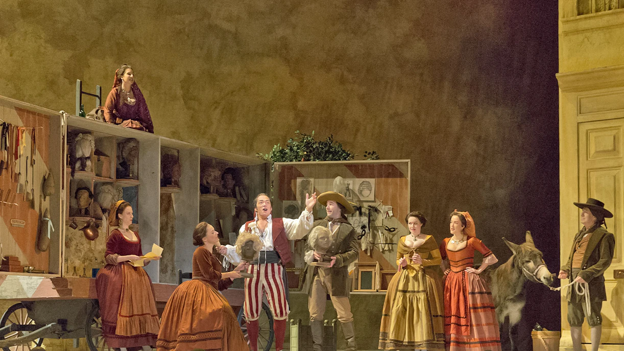 Opera performers on stage during Il Barbiere Di Siviglia with costumes and props.
