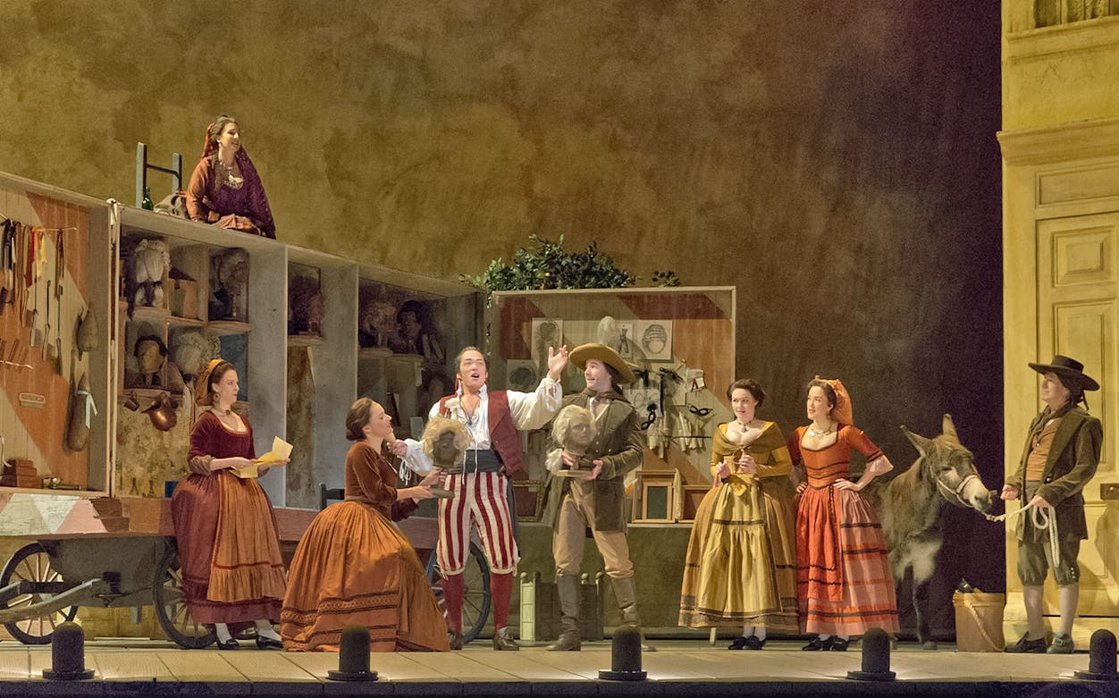 Opera performers on stage during Il Barbiere Di Siviglia with costumes and props.