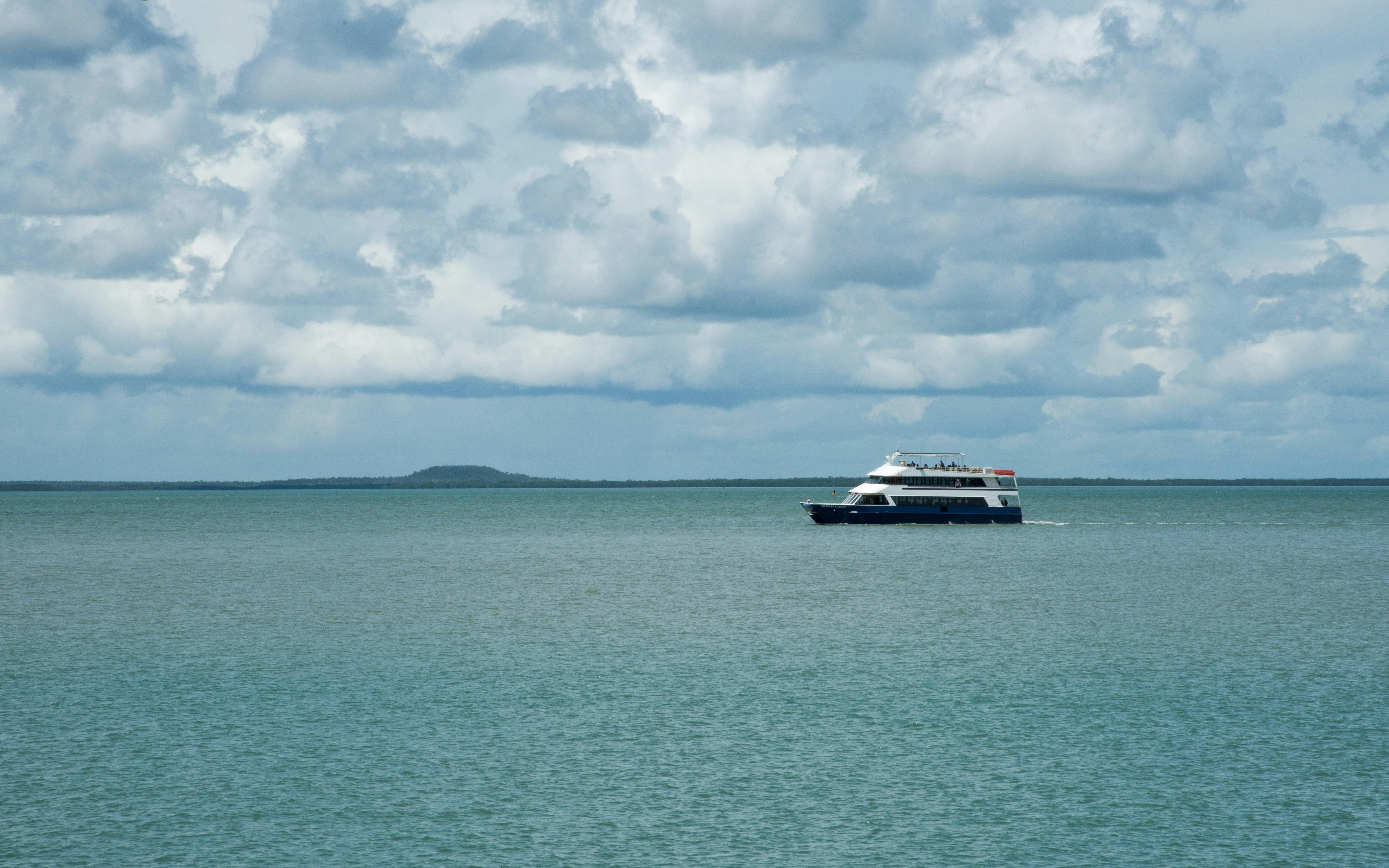 Cruise ship sailing on Darwin Harbour under cloudy skies.