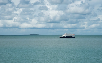 Cruise ship sailing on Darwin Harbour under cloudy skies.
