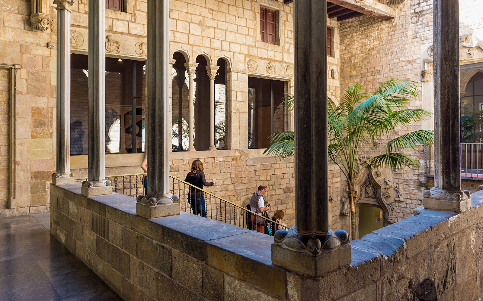 Tourists with guide exploring courtyard of Picasso Museum in Barcelona.