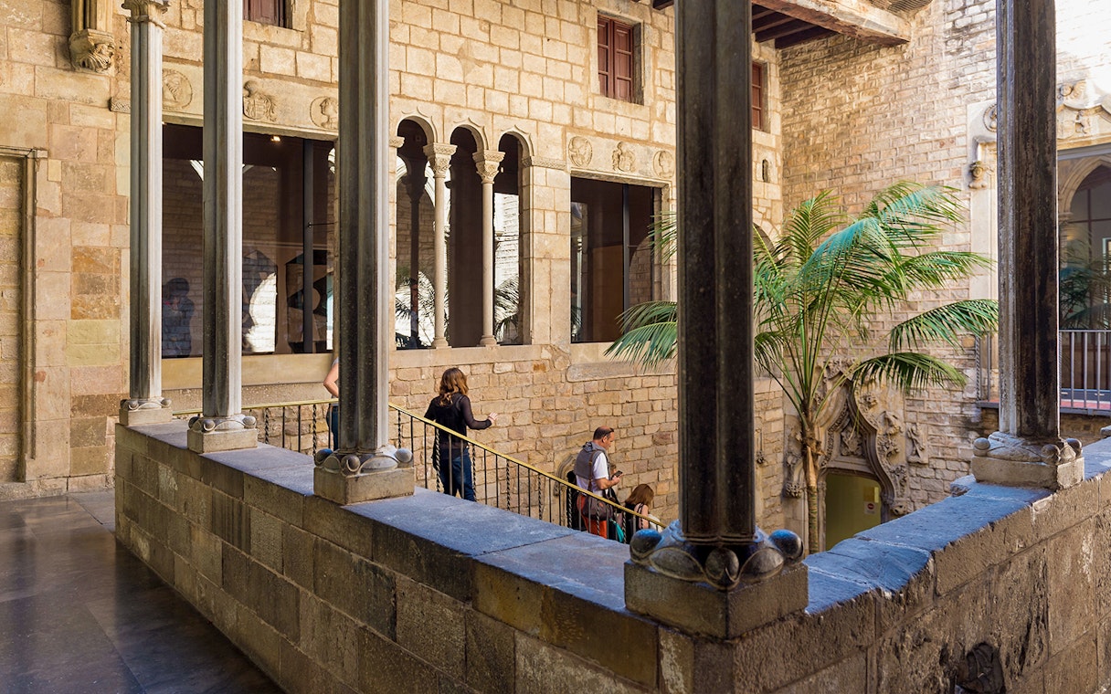 Tourists with guide exploring courtyard of Picasso Museum in Barcelona.