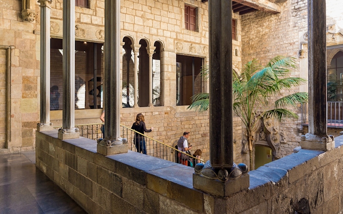Tourists with guide exploring courtyard of Picasso Museum in Barcelona.
