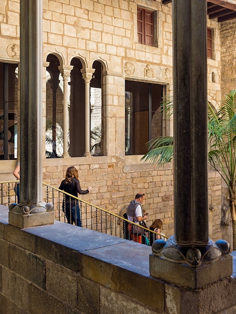 Tourists with guide exploring courtyard of Picasso Museum in Barcelona.
