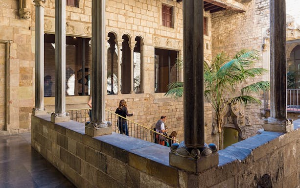 Tourists with guide exploring courtyard of Picasso Museum in Barcelona.