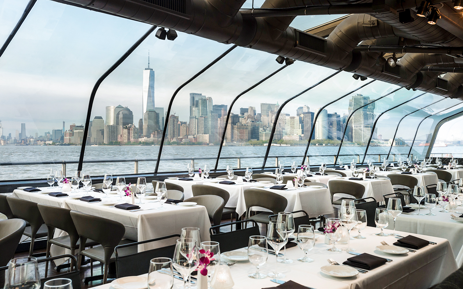 Elegant dining setup on Bateaux New York cruise with city skyline view.