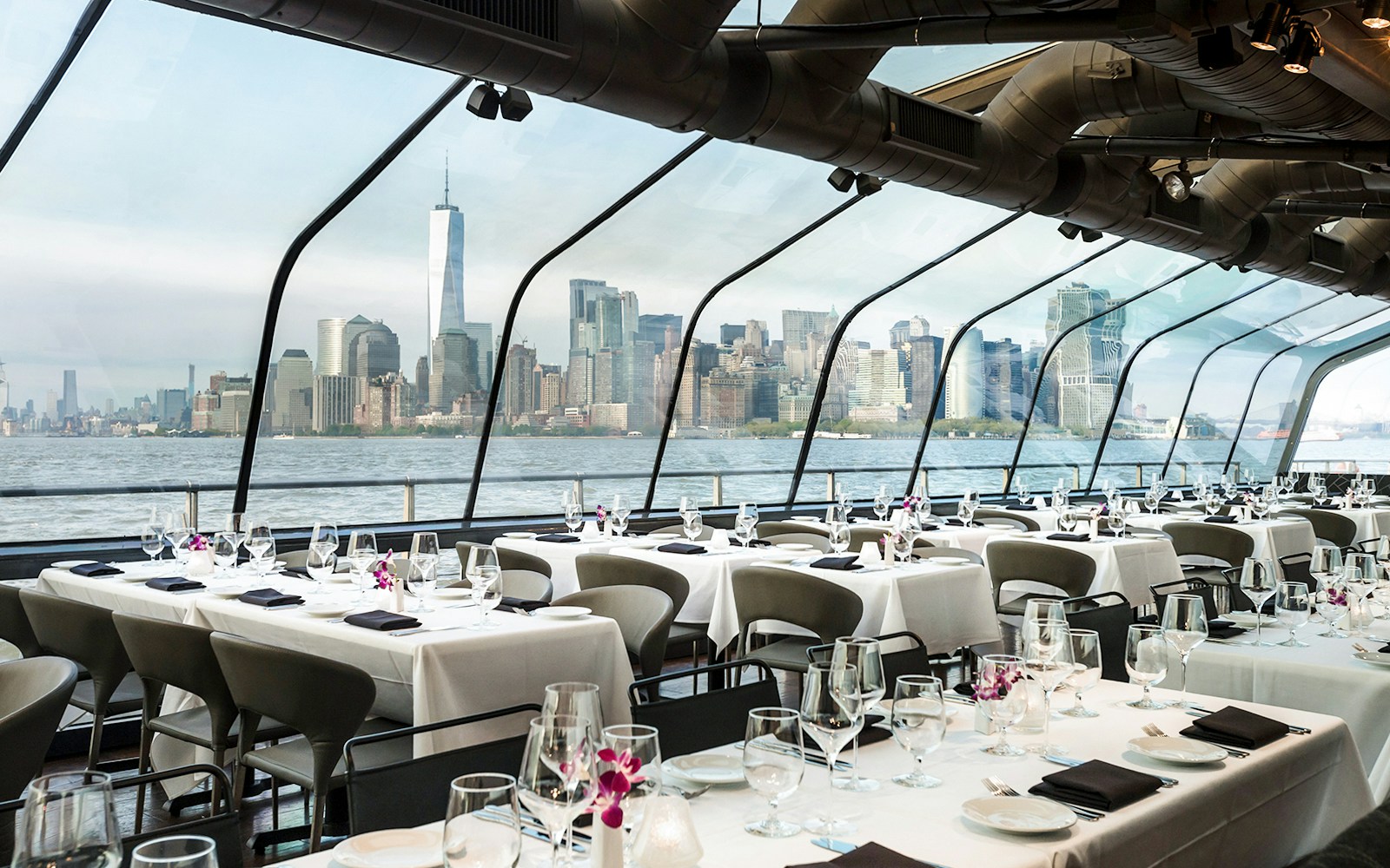 Elegant dining setup on Bateaux New York cruise with city skyline view.