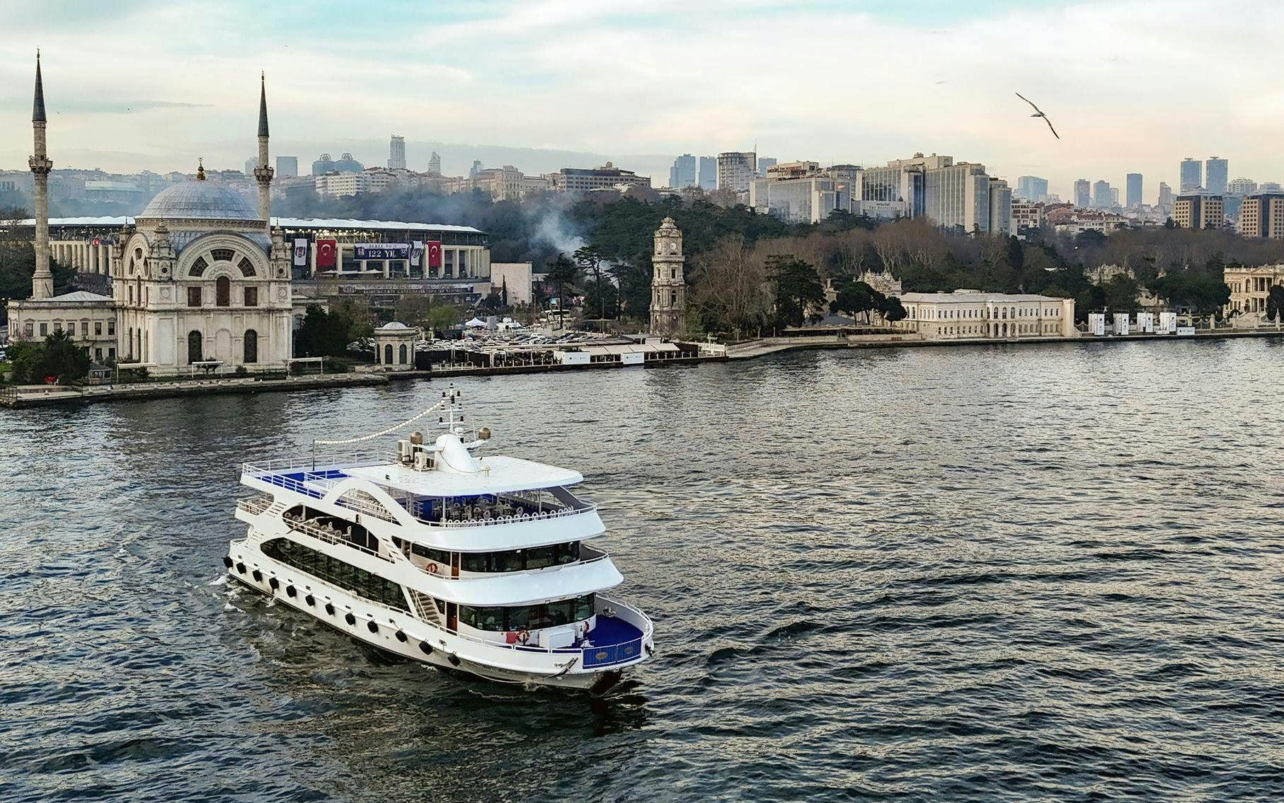 Luxury cruise ship on the Bosphorus with Istanbul skyline and mosque in the background.