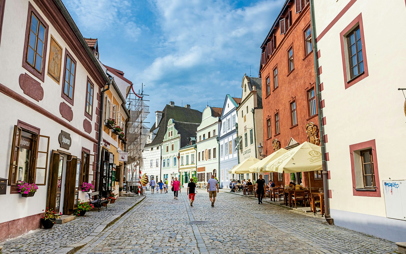 Tourist walking through cobblestone streets of Cesky Krumlov, Czech Republic, with historic buildings in view.