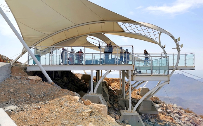 Zipline platform with visitors at Jebel Jais, Ras al Khaimah, overlooking rocky landscape.