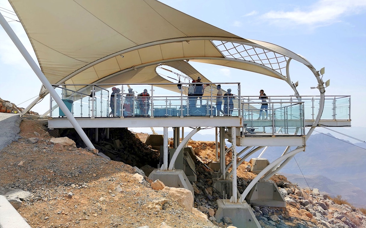 Zipline platform with visitors at Jebel Jais, Ras al Khaimah, overlooking rocky landscape.