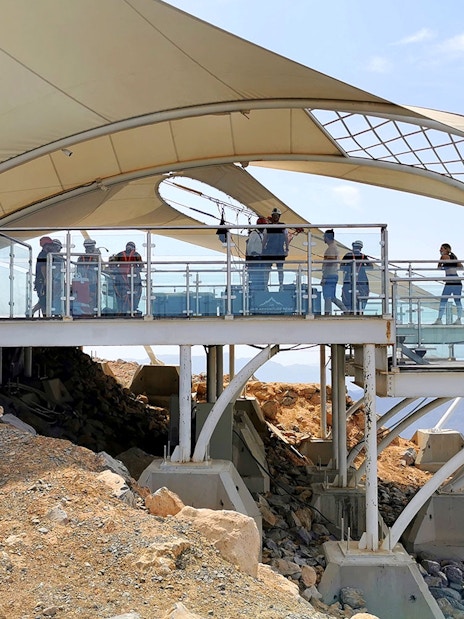 Zipline platform with visitors at Jebel Jais, Ras al Khaimah, overlooking rocky landscape.