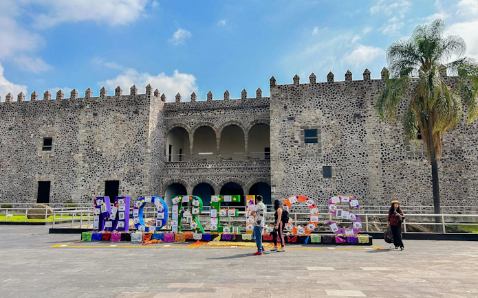 Cuernavaca's Palacio de Cortés with colorful "Morelos" sign in front, Mexico City tour.