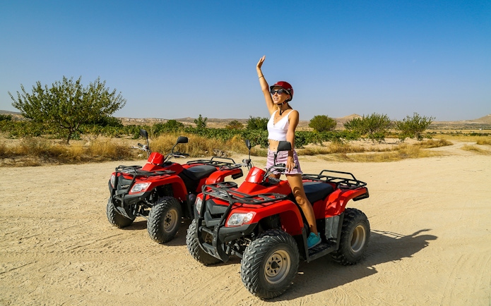 Person on ATV in Cappadocia desert landscape, part of Red Tour experience.