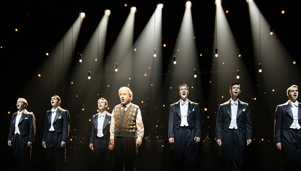 Performers singing on stage under spotlights in "Harmony: A New Musical".